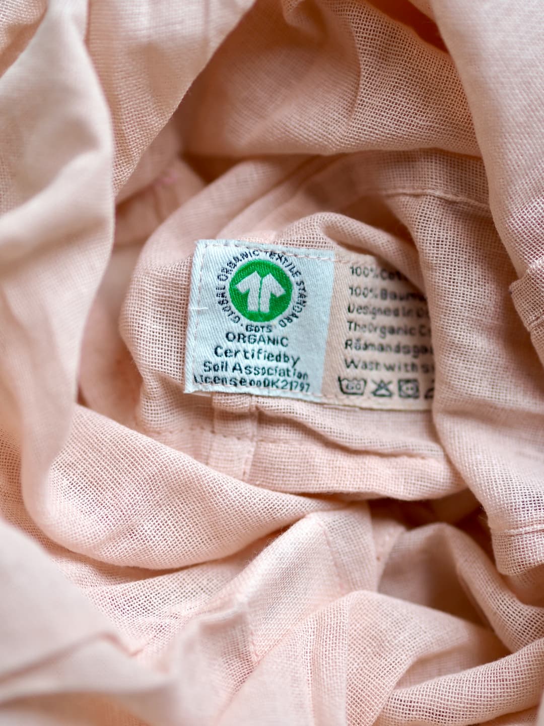 Various clothing labels displaying certifications for organic and sustainable cotton production.